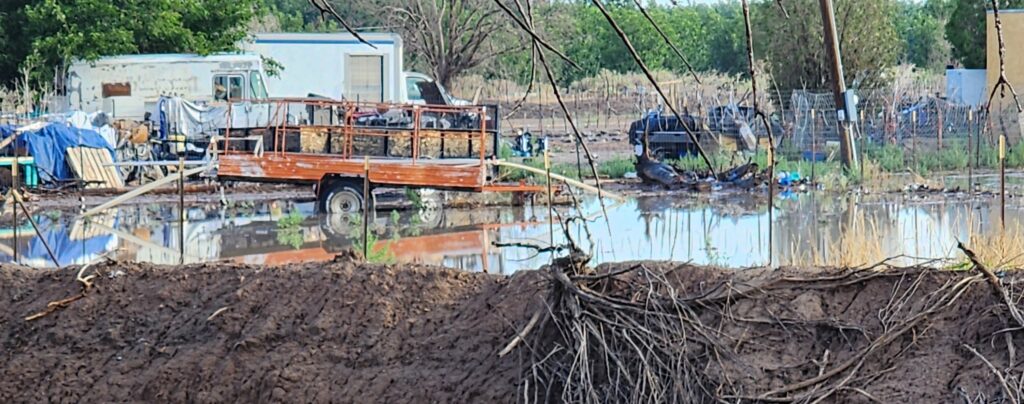 Neighbors yard filled with junk and old vehicles deep in rainwater